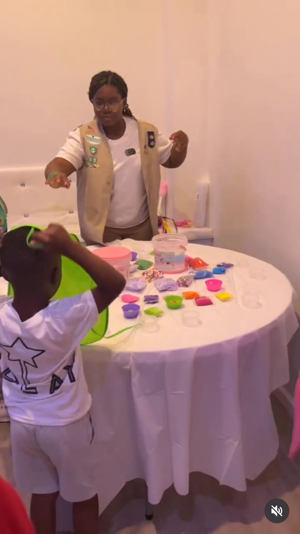 A Starplay crew member in uniform hosting a slime station, with trays of colourful mix-ins on a round table.